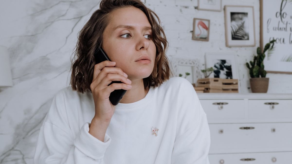 Genç bir kadının elinde akıllı telefon, ekranda pil yüzdesi ve güç tasarrufu simgesi görünüyor, doğal gün ışığı